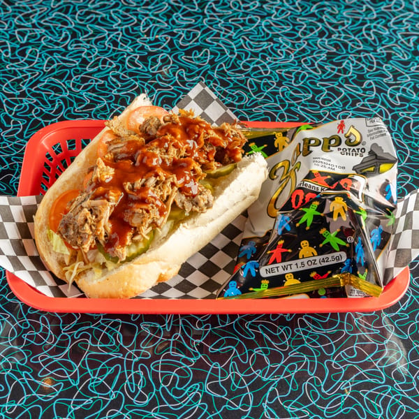 Miss Delta's pulled pork po'boy with BBQ sauce, pickles, and a bag of Zapp's chips.